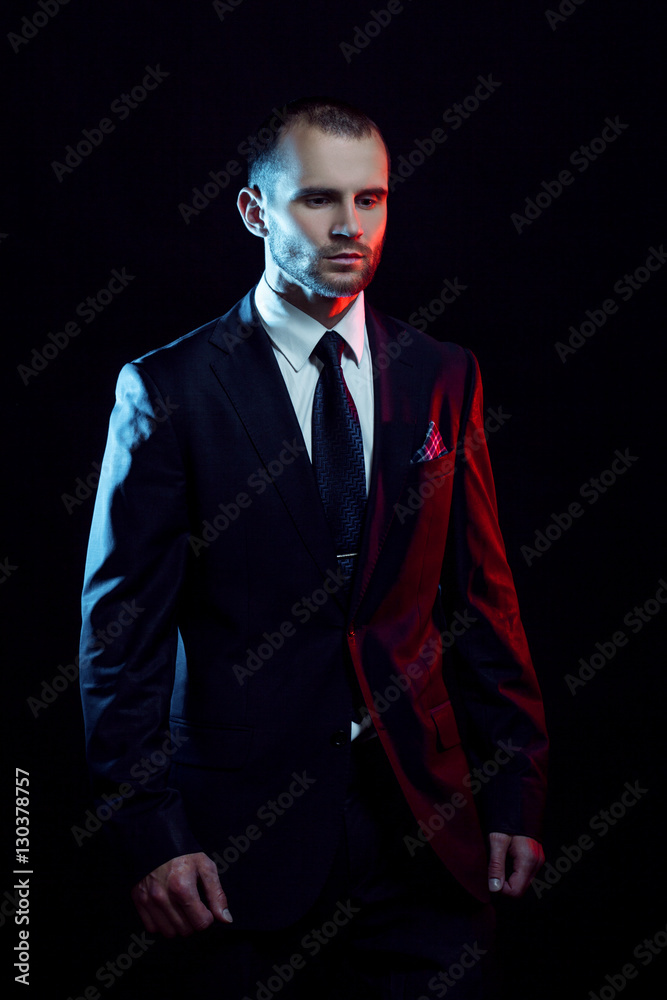 serious man in a business suit, dark background, backlight blue and red tones serious man in a business suit, dark background, backlight blue and red tones