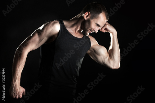 muscular man, shows his biceps, black background