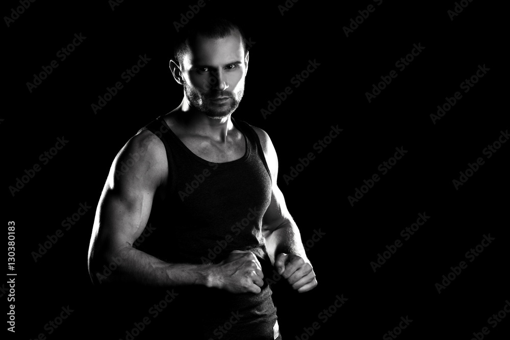 muscular man, clasps hands in fist, black and white toning muscular man, clasps hands in fist, black and white toning