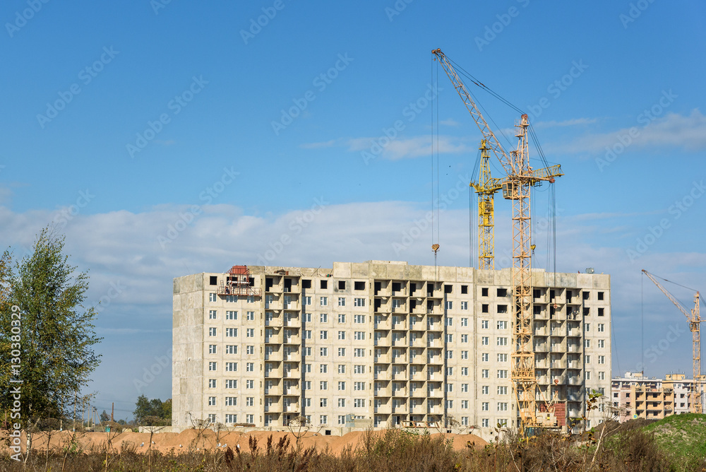 construction of apartment buildings and crane on blue sky background