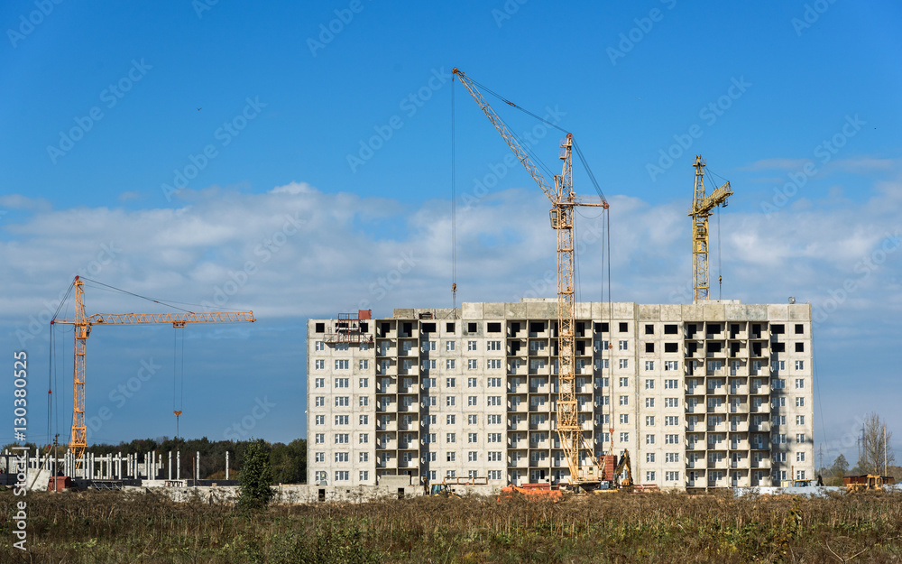 Building crane and apartment house under construction against sky Building crane and apartment house under construction against sky