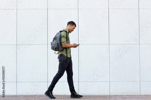 smiling man walking with backpack smart phone and headphones photo