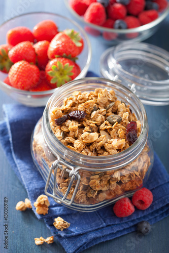 homemade healthy granola in glass jar and berries