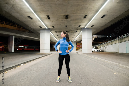 Young runner under the bridge in the evening, resting