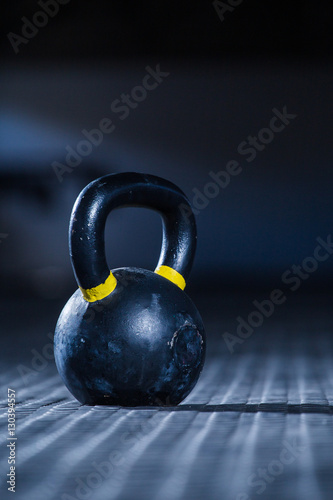 Fototapeta Naklejka Na Ścianę i Meble -  Kettle bell weight in a dark gym with moody and edgy lighting