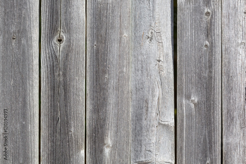 Grayed weathered cedar fencing with knots and cracks.