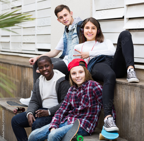 girl and three boys hanging out outdoors and discussing somethin photo