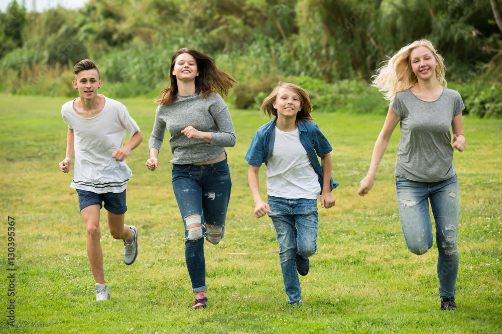 Teenagers running on green lawn in park .