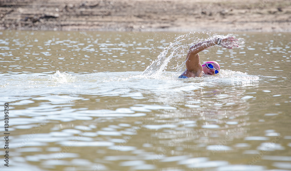 Female triathlete swimming in a dam while competing in a triathlon