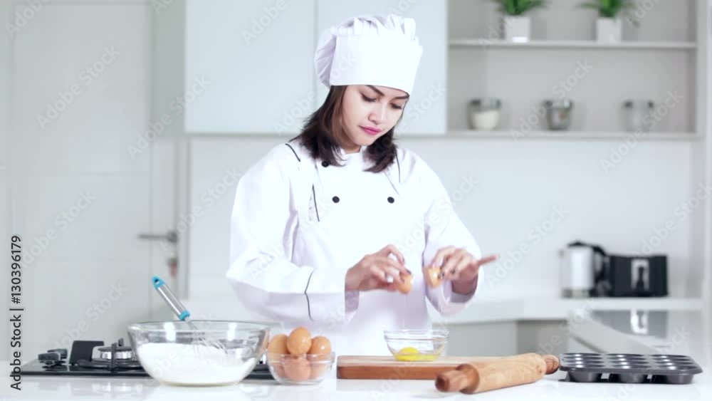 Pretty young woman making cake in the kitchen and break an egg on a bowl
Pretty young woman making cake in the kitchen and break an egg on a bowl