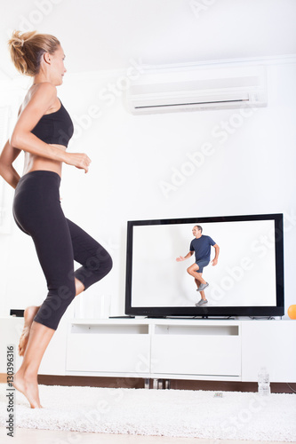 femme qui fait du sport en courant devant sa télévision © plprod