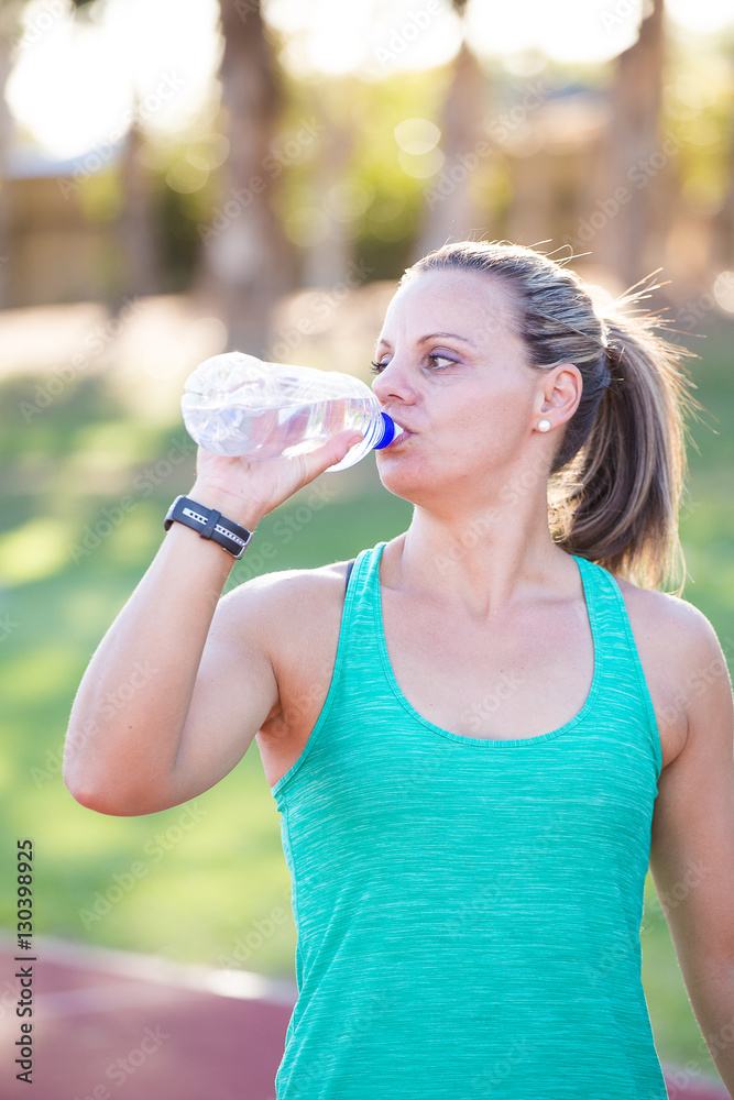 Fit Female fitness model drinking water right before she starts training Fit Female fitness model drinking water right before she starts training