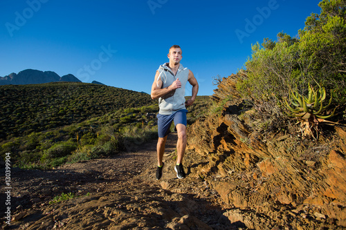 Male cross country athlete running in the hills on a warm and su