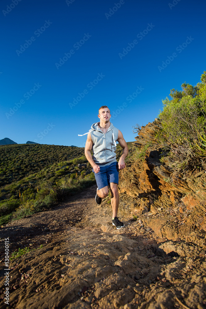 Male cross country athlete running in the hills on a warm and su