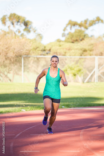 Fit female athlete running a sprint race on a tartan athletics track © Dewald