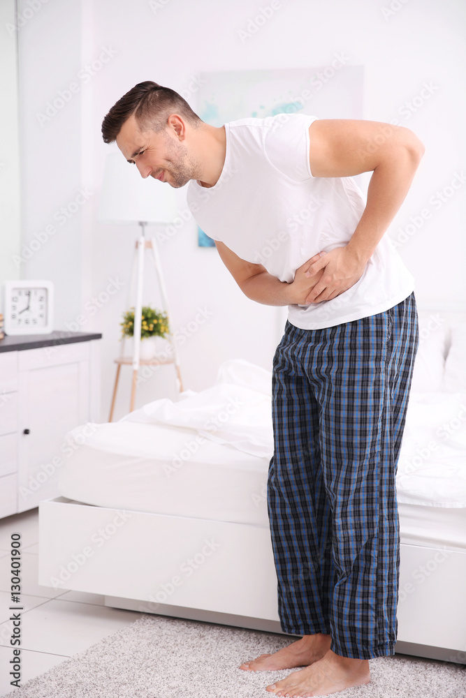 Obraz premium Handsome man feeling stomachache pain at home