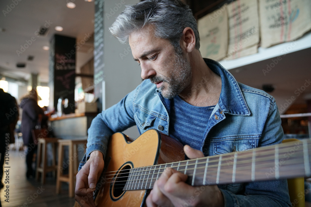 Obraz premium Mature trendy guy playing the guitar in a bar
