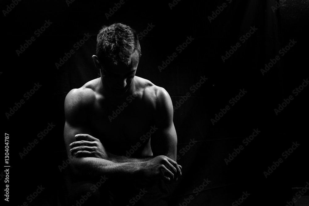 Fototapeta premium Male fitness model showing muscles in studio with a black backgr