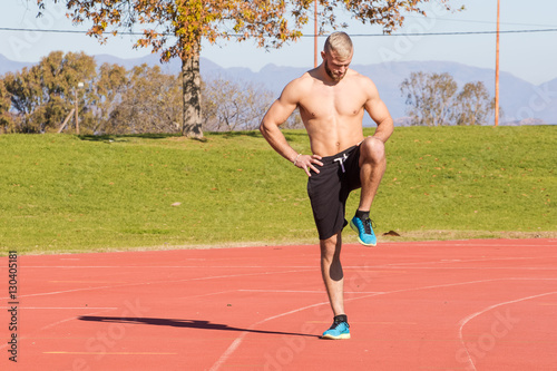 Male Athlete sprinting on a tartan athletics track on a bright s
