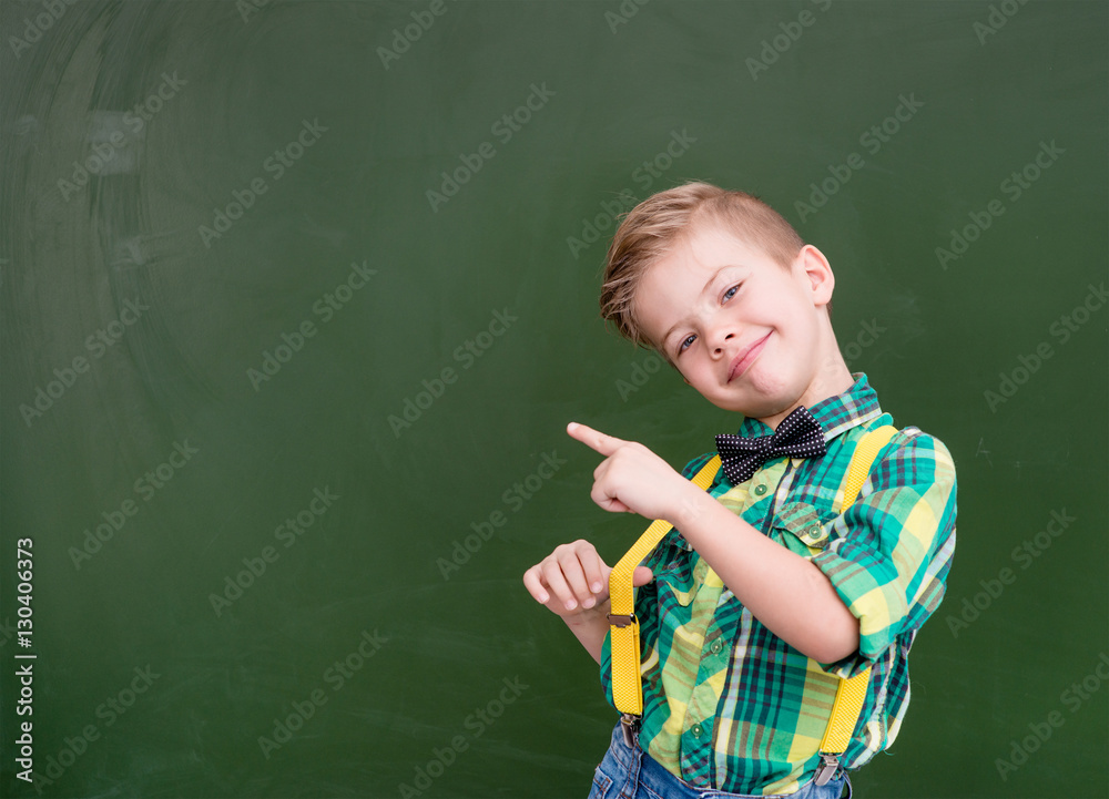 Young boy points on empty green chalkboard Young boy points on empty green chalkboard