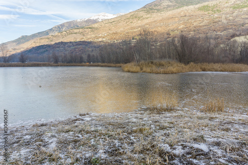 park with a frozen lake in the winter and mountains background