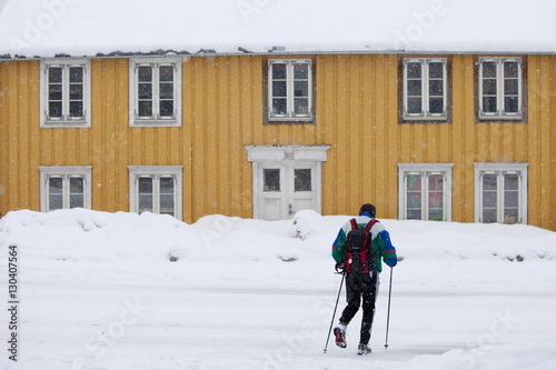 Man with walking poles passes traditional wooden buildings on Storgata in the quaint area of Tromso, Arctic Circle, Northern Norway photo