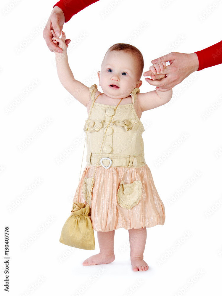 Little girl learns to walk, taking its first steps. Female hands mother support the child