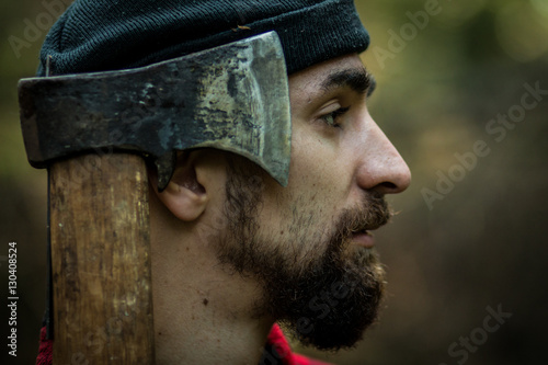 portrait of a man - lumberjack with an ax in the forest, side view