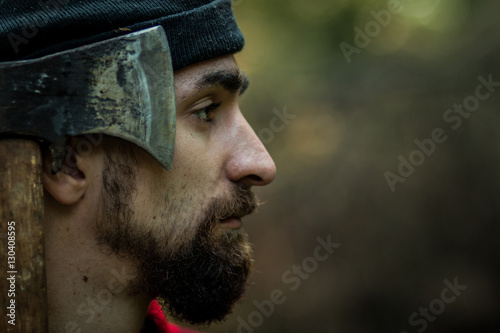 portrait of a man - lumberjack with an ax in the forest, side view