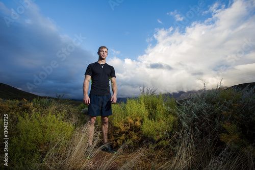 Male fitness model running allong a trail in the field, wearing © Dewald