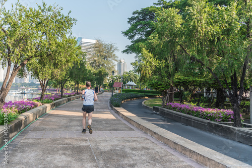 Unidentified old man is running in city park with smart gadget for healthy concept