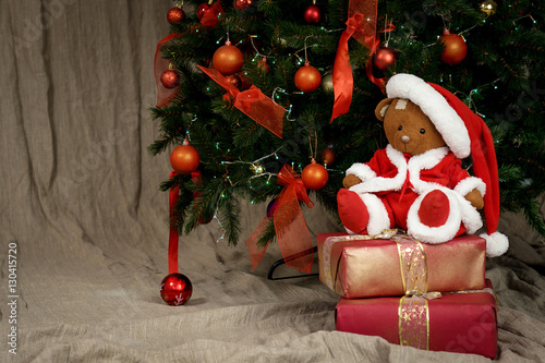 Teddy bear in a Santa suit under the Christmas tree 
