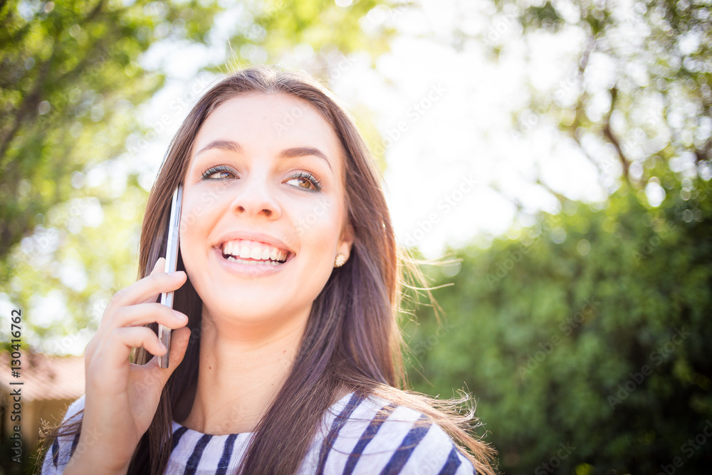 Pretty young millennial female model talking on her smart phone outside and taking selfies on her smart phone for social media Pretty young millennial female model talking on her smart phone outside and taking selfies on her smart phone for social media