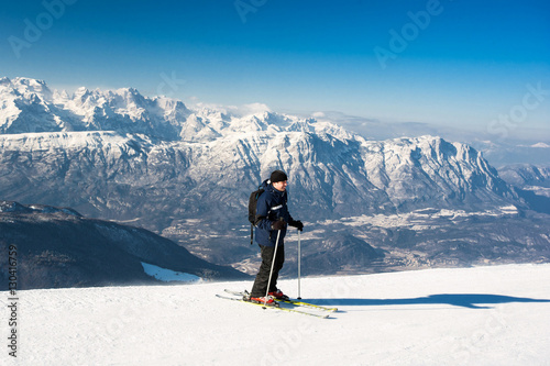 Man skier goes down from top of snow mountain on skis against th