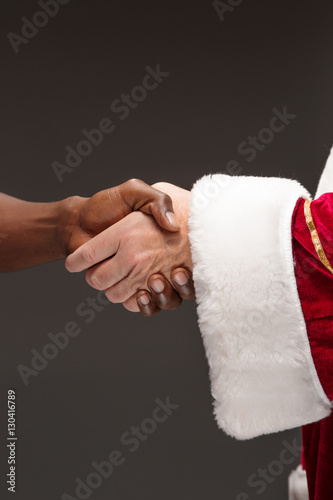 The handshake of Santa Claus hand and hand of african man