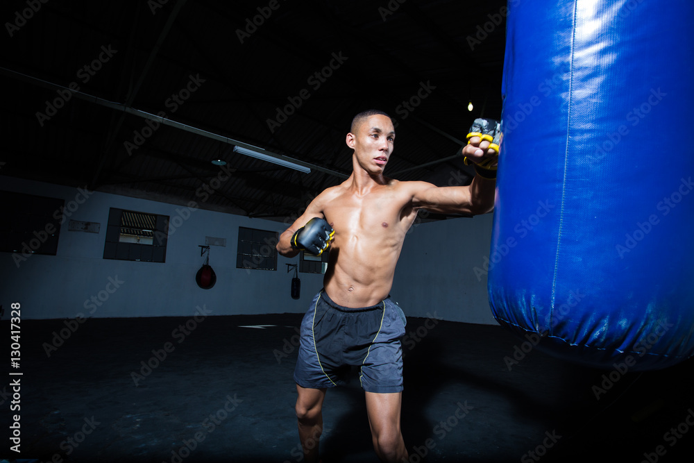 Male Athlete boxer punching a punching bag in a gym