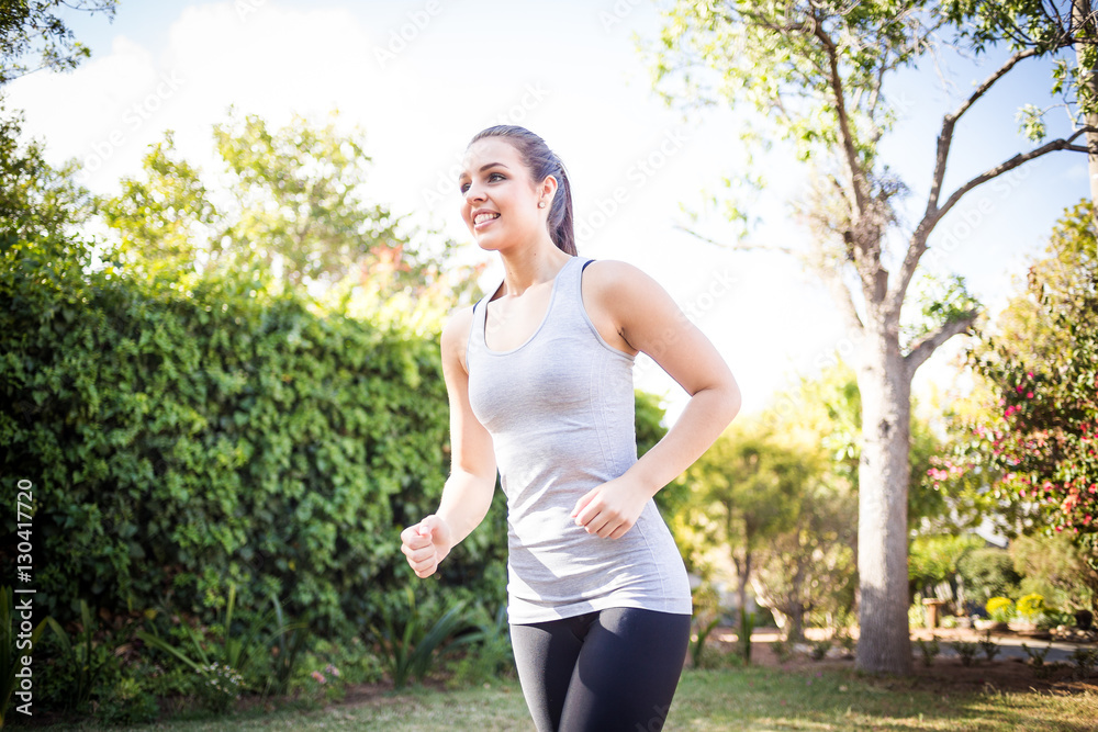 Female fitness model running and jumping in a street in a suburban area while training Female fitness model running and jumping in a street in a suburban area while training