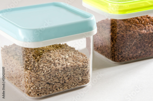Food storage. Food ingredients (spelt wheat and brown rice) in plastic containers. Selective focus.