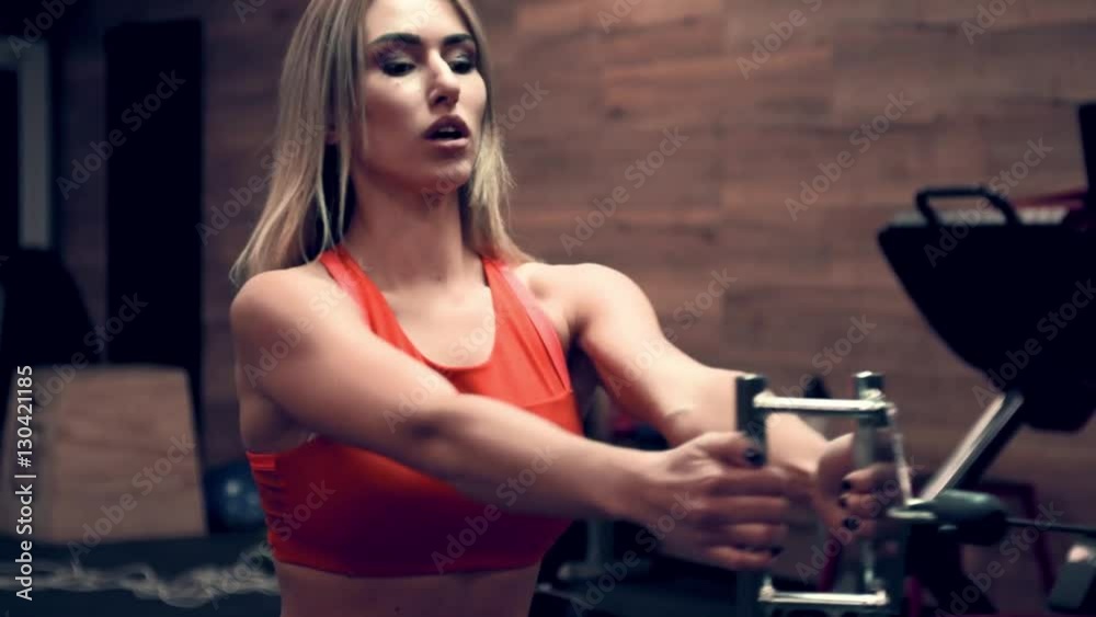 Muscular woman in a red top working out in the gym lifting weights Muscular woman in a red top working out in the gym lifting weights