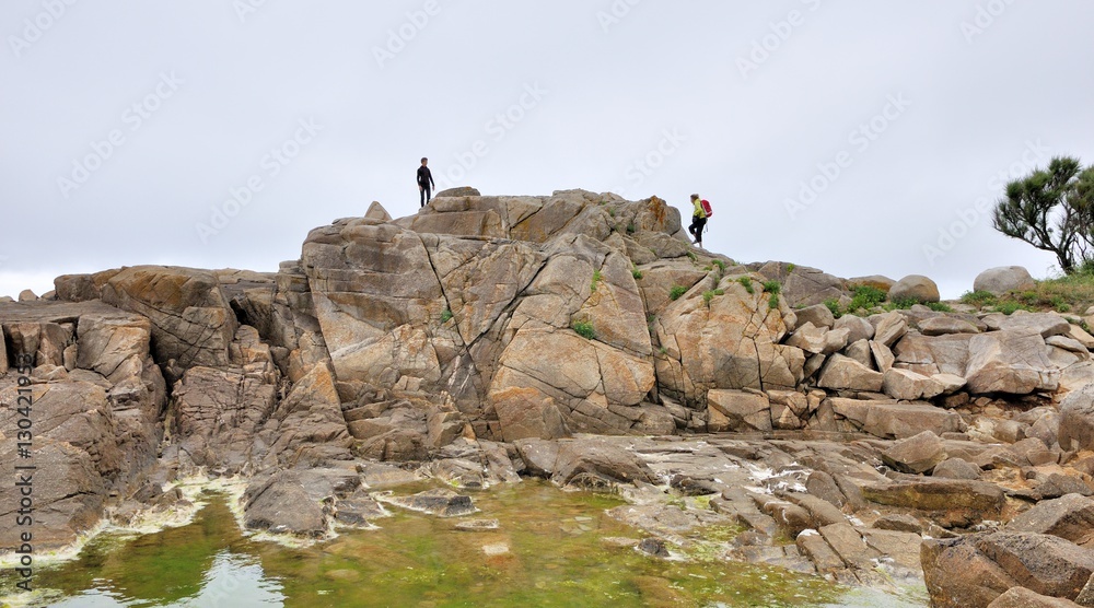 Deux jeunes jouent en haut d'un gros rochers à marée basse