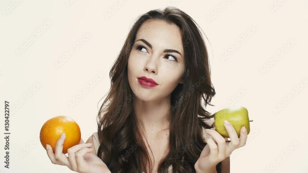 Young beautiful blonde girl choosing between apple and orange Young beautiful blonde girl choosing between apple and orange