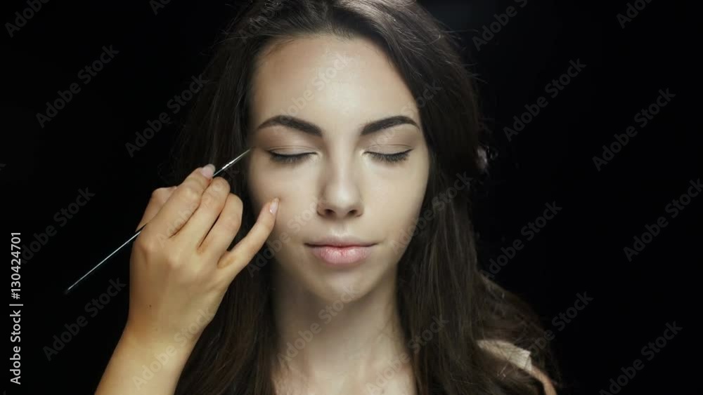 Make up artists hand applying eye liner on a female model face Make up artists hand applying eye liner on a female model face