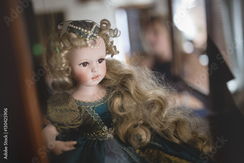 porcelain doll sitting in glass cabinet © MichelUlman