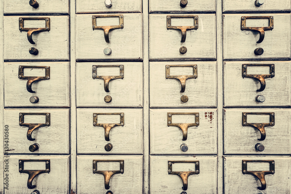 Obraz premium Rows of little drawers with white empty tags in an old furniture module, Vintage style...