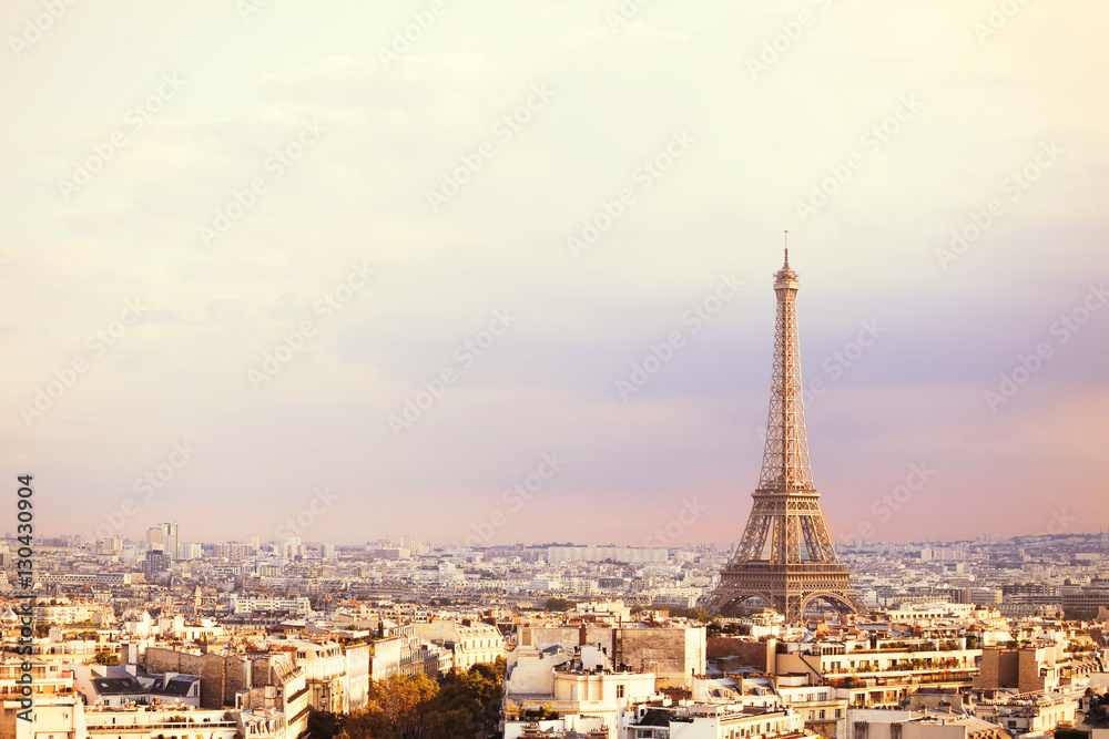 Fototapeta premium Wieża Eiffla o zachodzie słońca i widok na Paryż tworzą Łuk Triumfalny. Wieża Eiffla z Champ de Mars, Paryż, Francja. Piękne romantyczne tło.