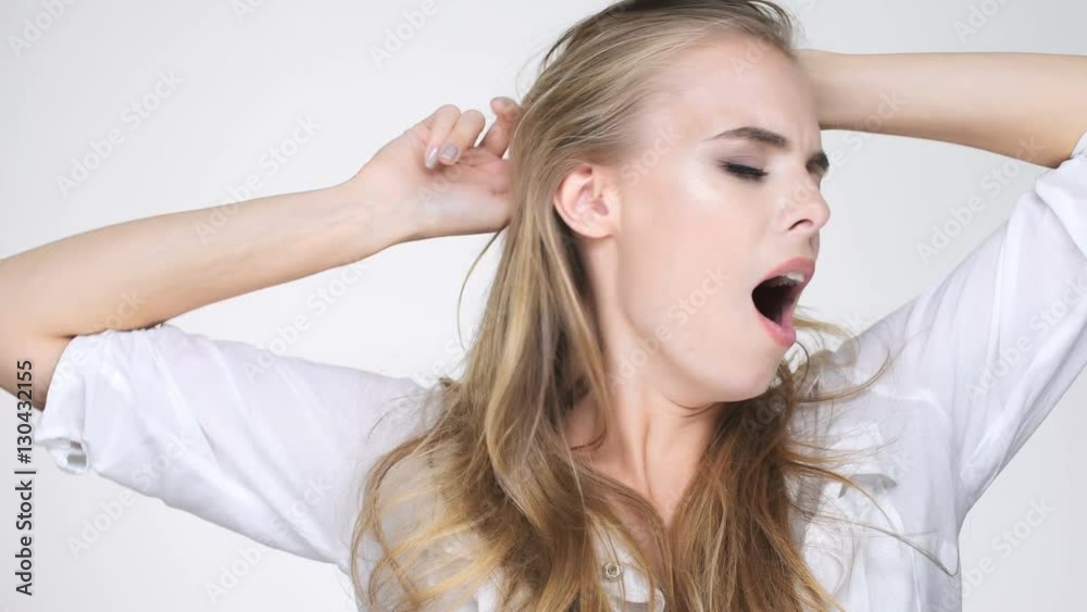 Beautiful young blonde woman in white shirt yawns of boredom Beautiful young blonde woman in white shirt yawns of boredom