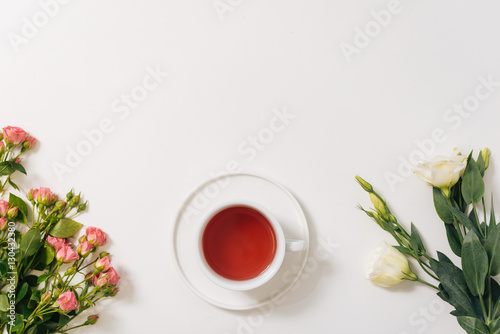 Flat lay of tea cup standing between flowers