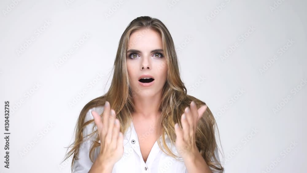 Astonished young blonde woman looking at camera with palms at her face 