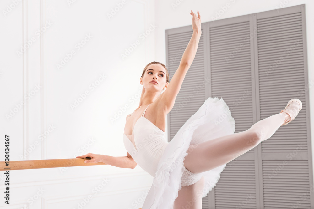 Young ballerina keeping her arm and leg in the air