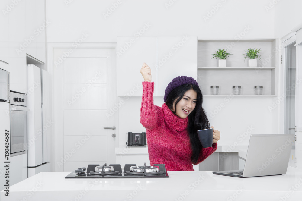 Cheerful woman with laptop in kitchen Cheerful woman with laptop in kitchen